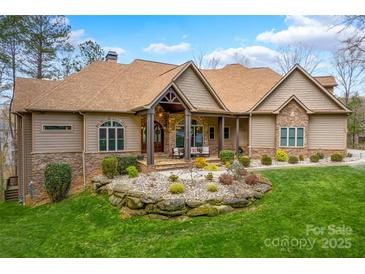 Charming single Gathering home featuring manicured landscaping, stone accents and a welcoming front porch at 135 Frostcliff Ln, Mooresville, NC 28117