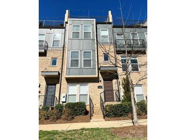Modern townhouse with a brick and gray exterior, featuring a small balcony and well-maintained landscaping at 2916 Grand Union Way, Charlotte, NC 28209