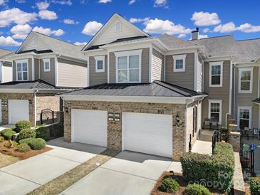 Charming brick-accented townhome featuring a two-car garage and well-maintained landscaping under a bright, partly cloudy sky at 45008 Wigeon Ln # 101, Indian Land, SC 29707