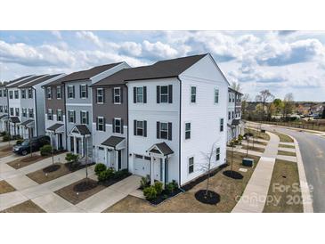 A row of townhouses featuring varied neutral tones, complemented by well-maintained landscaping and private garages at 13304 Porter Creek Rd, Charlotte, NC 28262