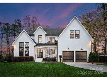 Stunning two-story modern farmhouse with black-framed windows and a manicured lawn at twilight at 209 Sardis Ln, Charlotte, NC 28270