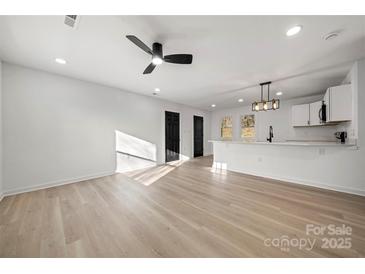 Open floor plan with new floors, a ceiling fan, and views into the modern kitchen at 2120 Green Oak Dr, Shelby, NC 28152