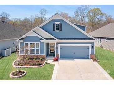 Charming blue two-story home featuring a two-car garage and beautifully landscaped front yard at 5025 Antebellum Dr, Iron Station, NC 28080