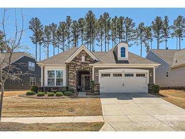 Charming single-story home featuring a stone facade and a well-maintained lawn and two-car garage at 525 Cellini Pl, Mount Holly, NC 28120