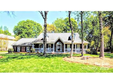 Charming brick home featuring a welcoming front porch and beautifully landscaped front yard at 5344 Saddlewood Ln, Mint Hill, NC 28227