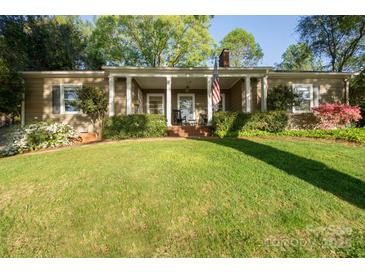 Charming single-story home featuring a covered front porch, well-manicured lawn, and vibrant landscaping at 631 Dogwood Rd, Statesville, NC 28677