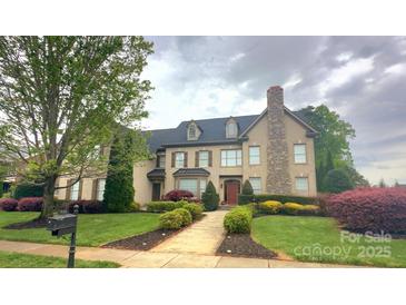 Stately two-story home with a stone chimney, manicured landscaping, and a welcoming front entrance at 708 Ridgelake Dr, Weddington, NC 28104
