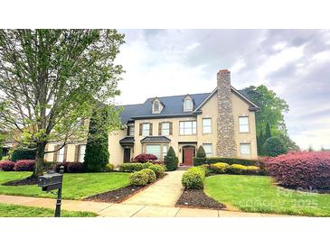 Charming two-story home with beautiful landscaping, a stone chimney, and a walkway to the front door at 708 Ridgelake Dr, Weddington, NC 28104