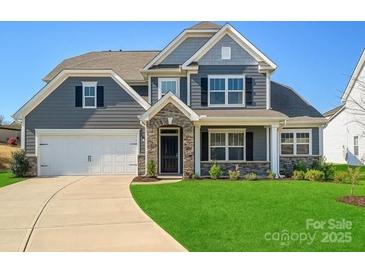 Charming two-story home features a manicured lawn, a two-car garage, and stylish stone accents at 104 Hemlock Cove Ct, Mooresville, NC 28117