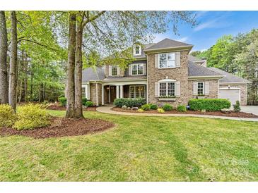 Charming brick two-story home with manicured lawn and lush landscaping offers great curb appeal at 107 Bare Foot Ln, Mooresville, NC 28117
