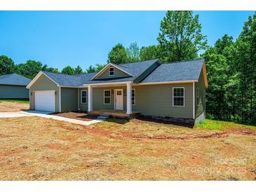Charming single-story home with a covered front porch and an attached garage, nestled among mature trees at 1127 Mckay Rd, Newton, NC 28658