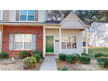 Charming townhome featuring a brick facade, green door, and well-maintained landscaping at 11630 Retriever Way, Charlotte, NC 28269