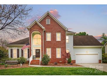 Charming two-story brick home featuring a welcoming front porch and a well-manicured lawn at 1214 Foxfield Rd, Waxhaw, NC 28173