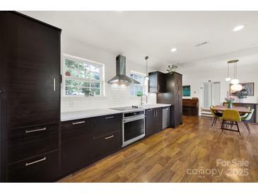 Modern kitchen featuring sleek, dark cabinetry, stainless steel appliances, and stylish pendant lighting at 2314 Wolfe St, Charlotte, NC 28205