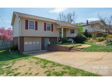 Charming two-story home boasts a brick facade, attached garage, and a well-manicured front yard at 409 Cardinal Dr, Newton, NC 28658