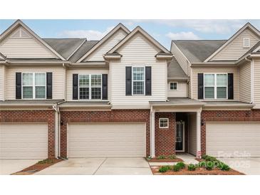 Charming townhome with a brick and vinyl facade, featuring an attached garage and a well-maintained lawn at 5951 Carrollton Ln, Charlotte, NC 28210