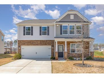 Two-story home featuring a two-car garage, stone accents, and a well-maintained front yard at 715 Saddlebred Ln, Locust, NC 28097