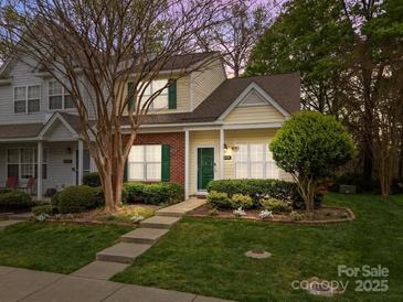 Charming townhome with brick and siding, green door and shutters, and landscaped front yard at 8230 Rudolph Rd, Charlotte, NC 28216