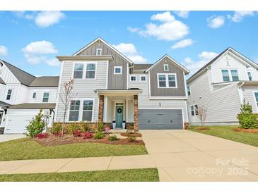 Charming two-story home featuring stone accents, a gray garage door, and manicured landscaping at 11036 Shreveport Dr, Huntersville, NC 28078