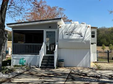 Charming home featuring a screened porch, white siding, black stairs, and landscaped front yard on a sunny day at 134 Putt Putt Ln, New London, NC 28127