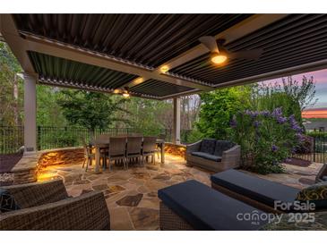 This outdoor patio features stone floors, ample seating, and an overhead pergola for comfortable outdoor living at 2035 Palace Way, Indian Land, SC 29707