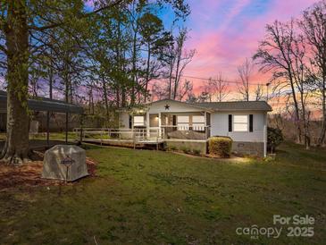 Charming single-story home featuring a screened porch, wheelchair ramp, and carport surrounded by trees at 404 Forest Winds Dr, Salisbury, NC 28144