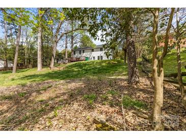 Spacious backyard features a lush lawn, mature trees, and a two-story home with a wooden deck at 6614 Old Providence Rd, Charlotte, NC 28226
