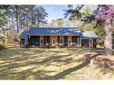 Beautiful home featuring a stylish dark gray exterior with a metal roof and contrasted by light wood trim at 7816 Wallace Ln, Charlotte, NC 28212