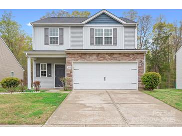 Inviting home features a 2-car garage, stone details, neutral siding and a neatly manicured lawn at 9230 Avery Meadows Dr, Charlotte, NC 28216
