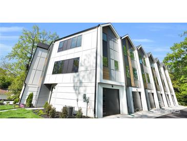Modern townhome featuring black garage doors, white siding, and tall windows at 3437 Byrnes St, Charlotte, NC 28205