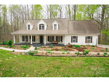 Charming home featuring a well-manicured lawn, a welcoming front porch with rocking chairs, and beautiful landscaping at 9820 Janeiro Dr, Huntersville, NC 28078