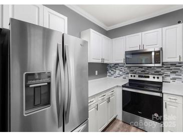 Updated kitchen featuring stainless steel appliances, white cabinets, and mosaic backsplash at 6359 Mallard View Ln, Charlotte, NC 28269