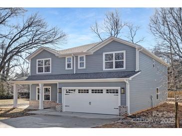 Two-story home featuring a two-car garage with brick accents and a light blue exterior, set against a backdrop of trees at 8007 Willhill Rd, Mint Hill, NC 28227