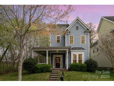 Charming two-story home features a welcoming porch, a well-manicured lawn, and beautiful landscaping at 9832 Sunriver Rd, Huntersville, NC 28078