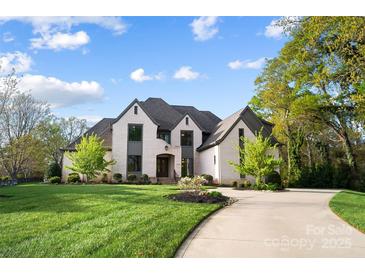 Stunning two-story home with a manicured lawn, circular driveway and a light colored brick exterior at 109 Redbird Ln, Weddington, NC 28104