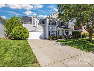 Charming two-story home with a well-manicured lawn and a long concrete driveway leading to an attached garage at 11222 Huntington Meadow Ln, Charlotte, NC 28273