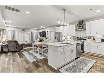 Bright, open kitchen with stainless appliances, island sink, and dining area flowing into the living room at 154 Shields Dr, Lincolnton, NC 28092