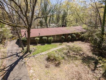 Expansive aerial view of a single-story home featuring a classic red roof and surrounded by lush greenery and mature trees at 340 Sardis N Rd, Charlotte, NC 28270