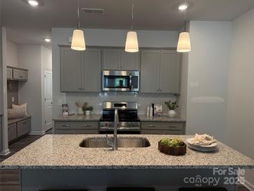 Modern kitchen featuring gray cabinets, stainless steel appliances, granite countertops, and pendant lighting at 5103 Orchardview Way # 27, Charlotte, NC 28216