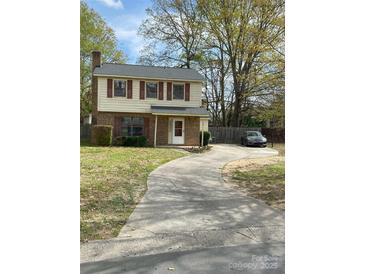 Charming two-story home with a brick and siding exterior, complemented by a long driveway and mature trees at 7307 Meadowland Dr, Charlotte, NC 28215