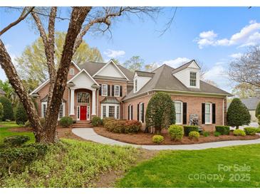 Stately brick home with a red door, black shutters, and manicured landscaping at 10809 Wicklow Brook Ct, Charlotte, NC 28277