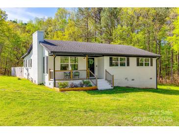 Charming one-story white brick home featuring a covered porch, black accents, and a lush green lawn at 1849 Harris Rd, Fort Mill, SC 29708