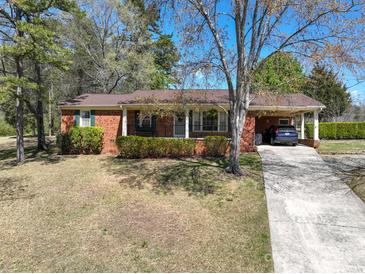 Charming brick home featuring a welcoming covered porch, lush landscaping, and a convenient carport on a sunny day at 206 Cliffside Dr, Kannapolis, NC 28081