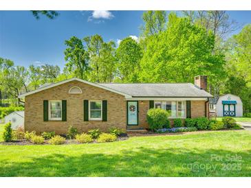 Charming brick ranch home with a well-manicured lawn and blossoming garden beds at 236 Greendale Dr, Mount Holly, NC 28120