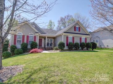 Charming home featuring a well-manicured lawn and red shutters enhancing its curb appeal on a sunny day at 7524 Common Oak Dr, Stanley, NC 28164