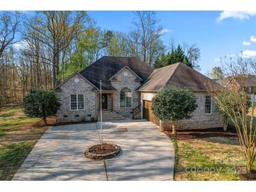 Charming brick home featuring a circular driveway, well-manicured lawn, and mature trees at 103 Devonshire Ln, Salisbury, NC 28146