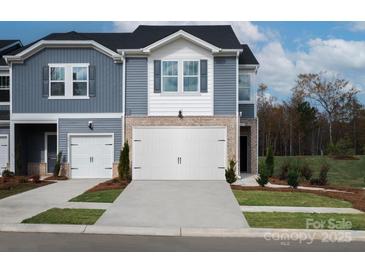 Charming townhome featuring a white garage door, brick accents, and blue siding at 1726 Braemar Village Dr, Monroe, NC 28110