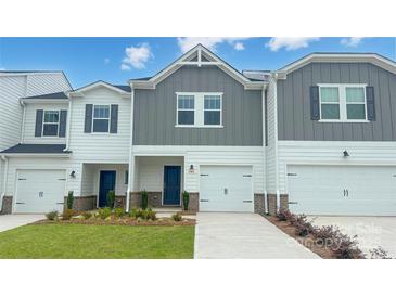 Charming townhome with well-manicured lawn, attached garage, and inviting blue front door at 1743 Braemar Village Dr, Monroe, NC 28110