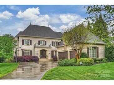 Charming two-story home featuring a stone facade, a two-car garage, and manicured landscaping under a cloudy blue sky at 20635 Queensdale Dr, Cornelius, NC 28031