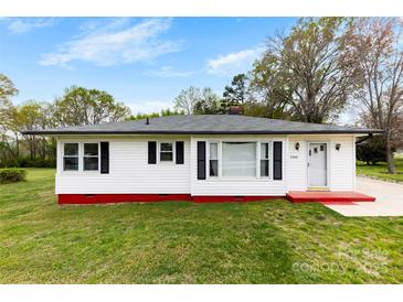 Charming single-story home features a red accent and black shutters, nestled among mature trees and a lush lawn at 2300 Linwood Rd, Gastonia, NC 28052